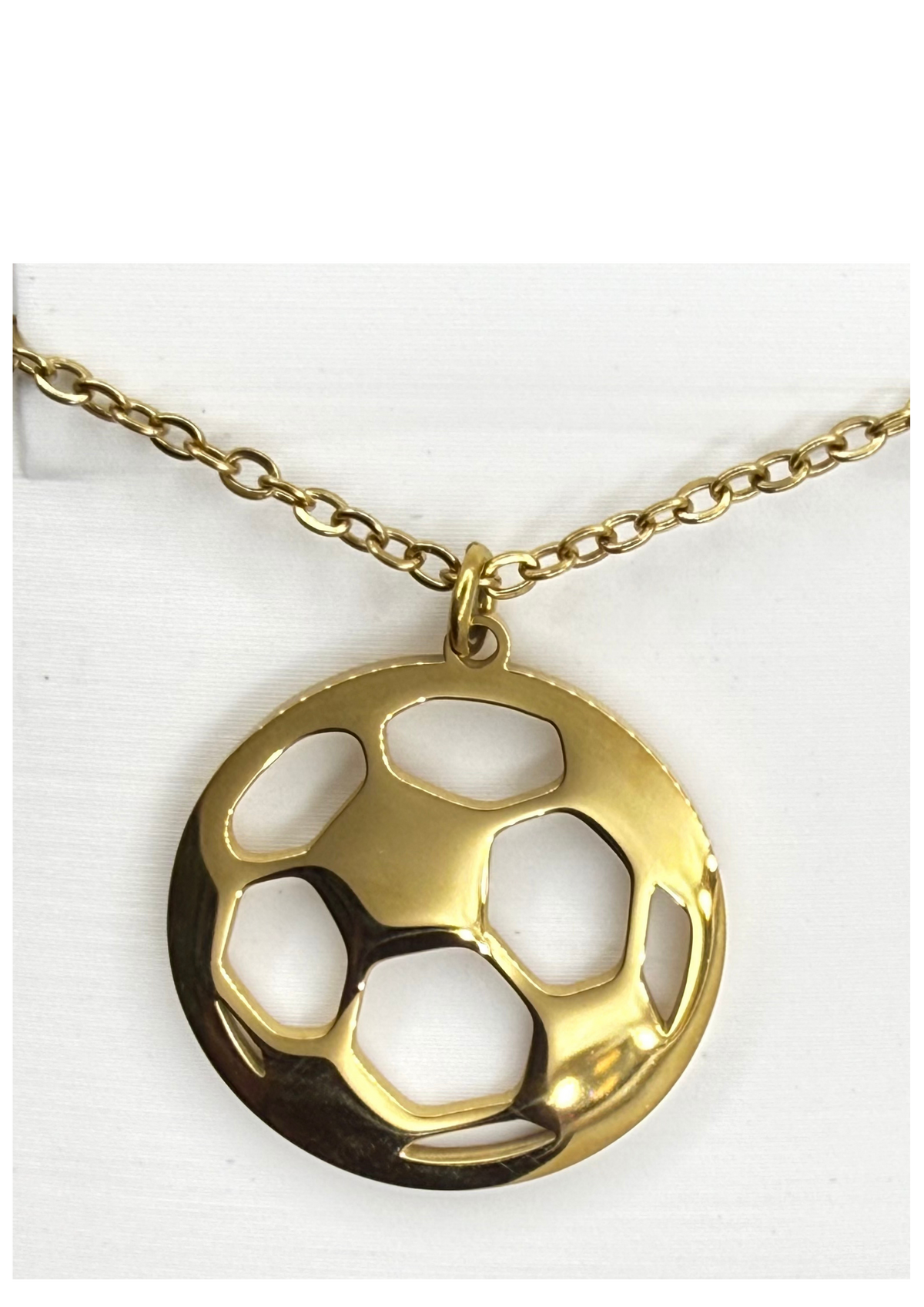 A gold soccer ball pendant necklace with a cutout design, hanging from a gold link chain against a white background.