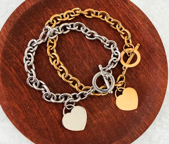 "Chunky chain link bracelet with polished heart tag charm and toggle clasp in gold-tone and silver-tone stainless steel"
