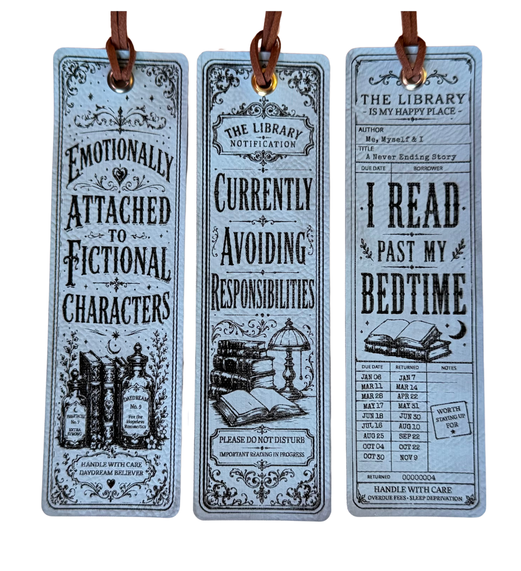 Three decorative hanging bookmarks with brown leather loops, shown against a plain white background. The bookmarks have a vintage illustrated design in pale blue-gray with black text and drawings, featuring phrases like 'Emotionally Attached to Fictional Characters' and 'I Read Past My Bedtime.