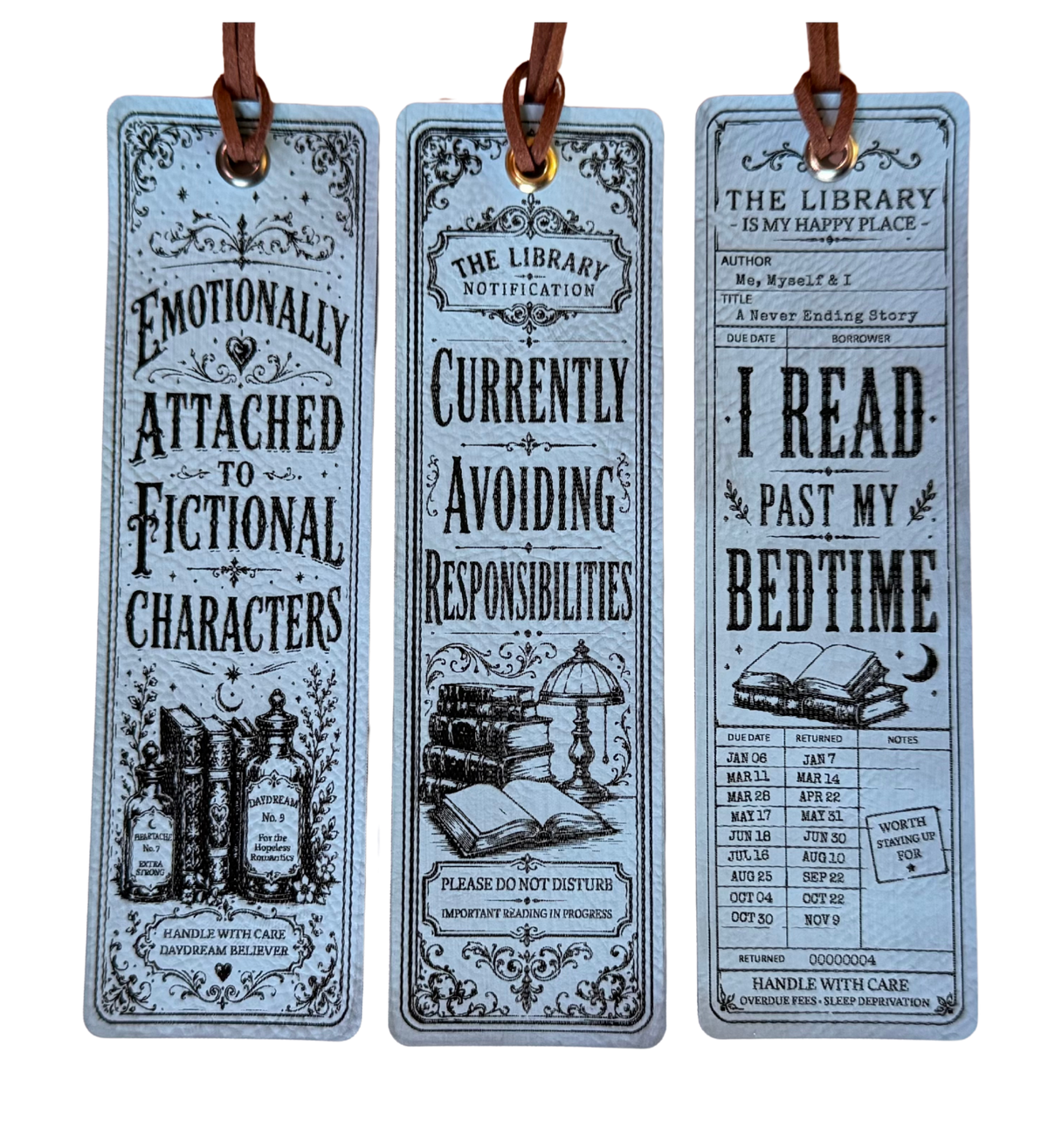 Three decorative hanging bookmarks with brown leather loops, shown against a plain white background. The bookmarks have a vintage illustrated design in pale blue-gray with black text and drawings, featuring phrases like 'Emotionally Attached to Fictional Characters' and 'I Read Past My Bedtime.
