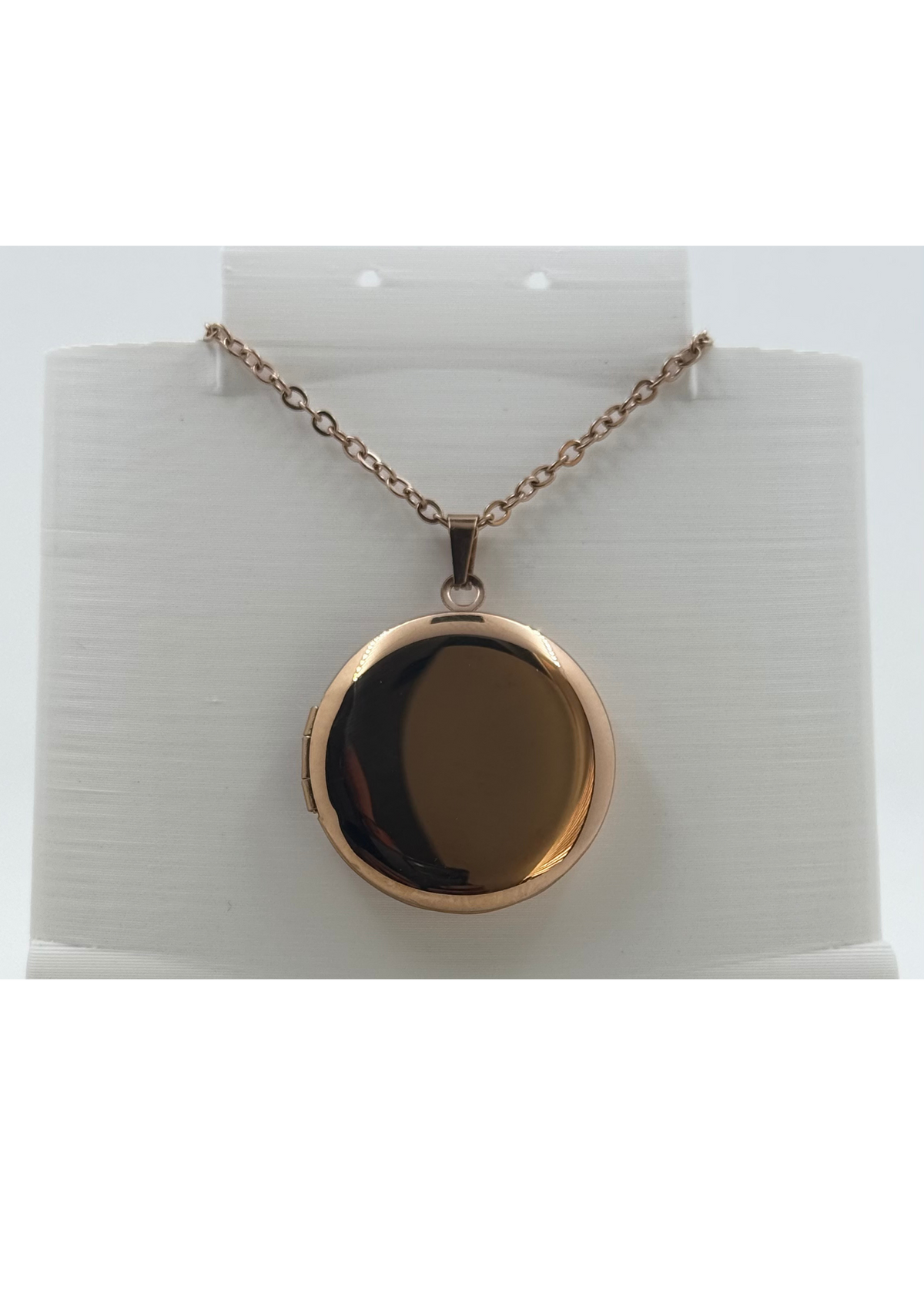 A rose gold oval locket pendant necklace on a delicate chain, displayed on a white cylindrical jewelry stand against a white background.