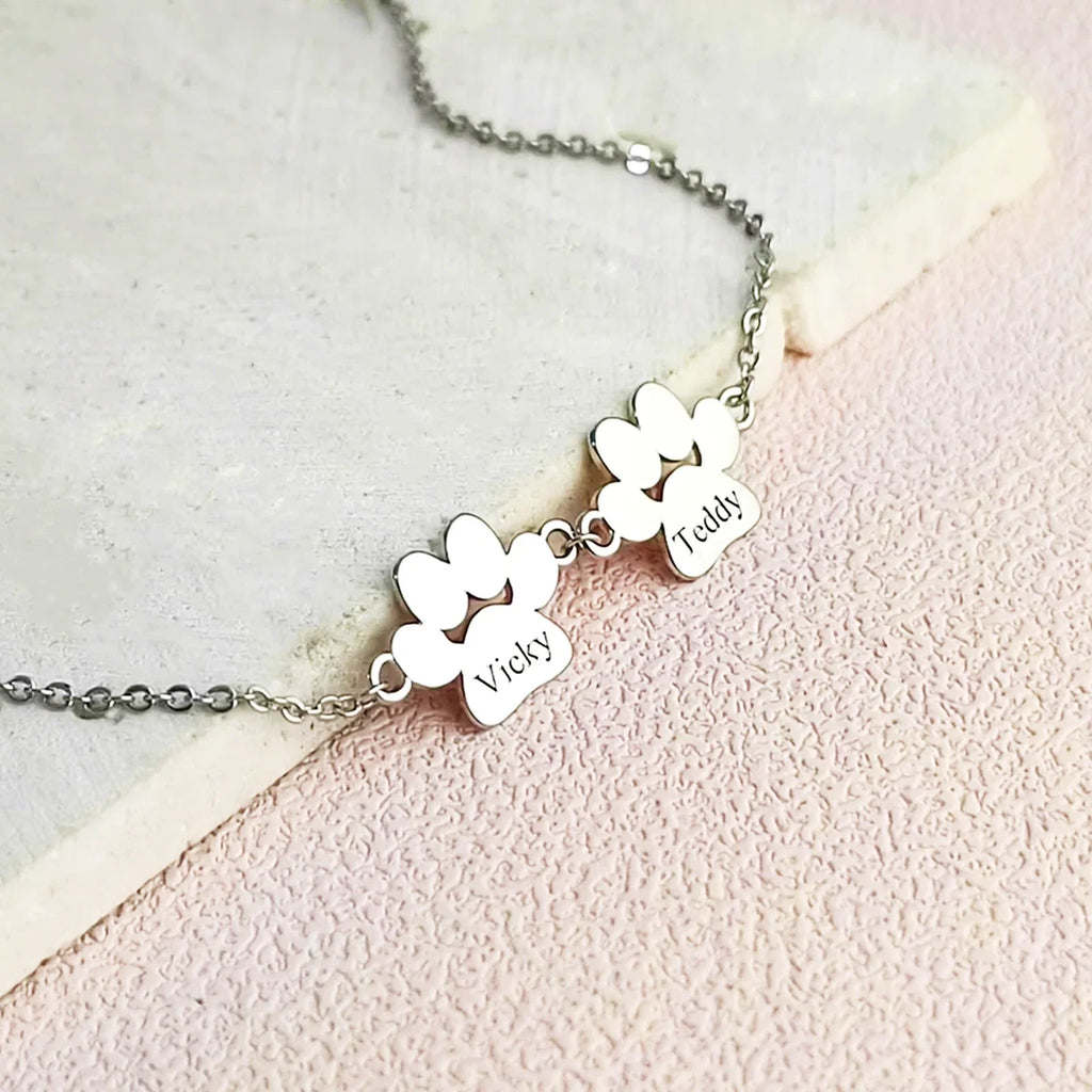 Silver necklace with three engraved heart-shaped pendants on a light pink background