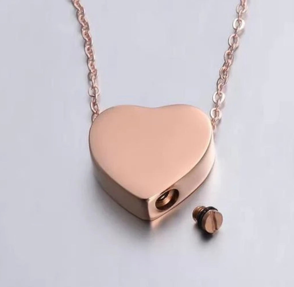 A rose gold heart-shaped pendant necklace with a matching chain and a small separate screw-back stud, shown on a light gray background.