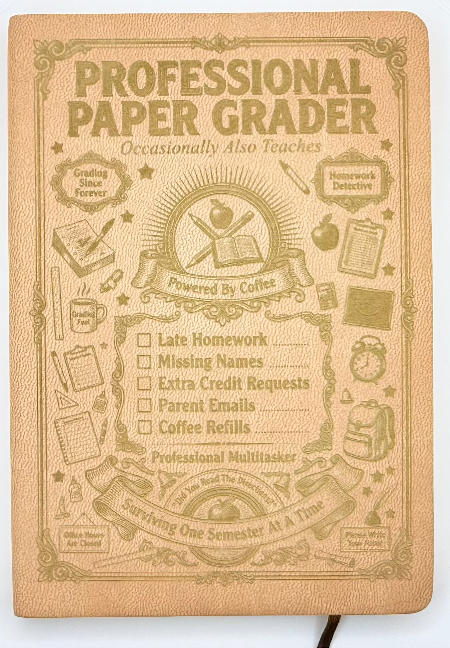A tan hardcover notebook titled 'PROFESSIONAL PAPER GRADER' with embossed vintage-style illustrations and checklist text on the cover, photographed against a plain white background.