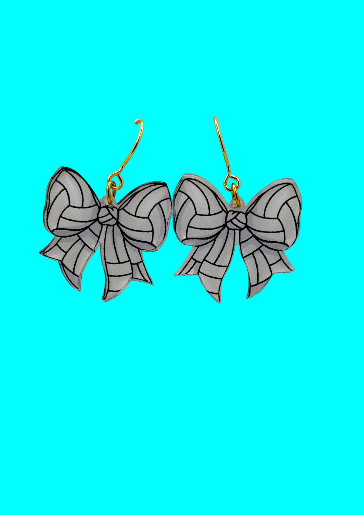 A pair of dangling bow earrings with white and black outlined bows and gold-tone hooks, displayed against a white textured background.