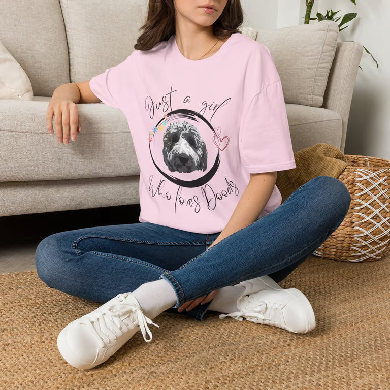 Person wearing a pink t-shirt with a motivational quote and graphic, sitting on the floor.